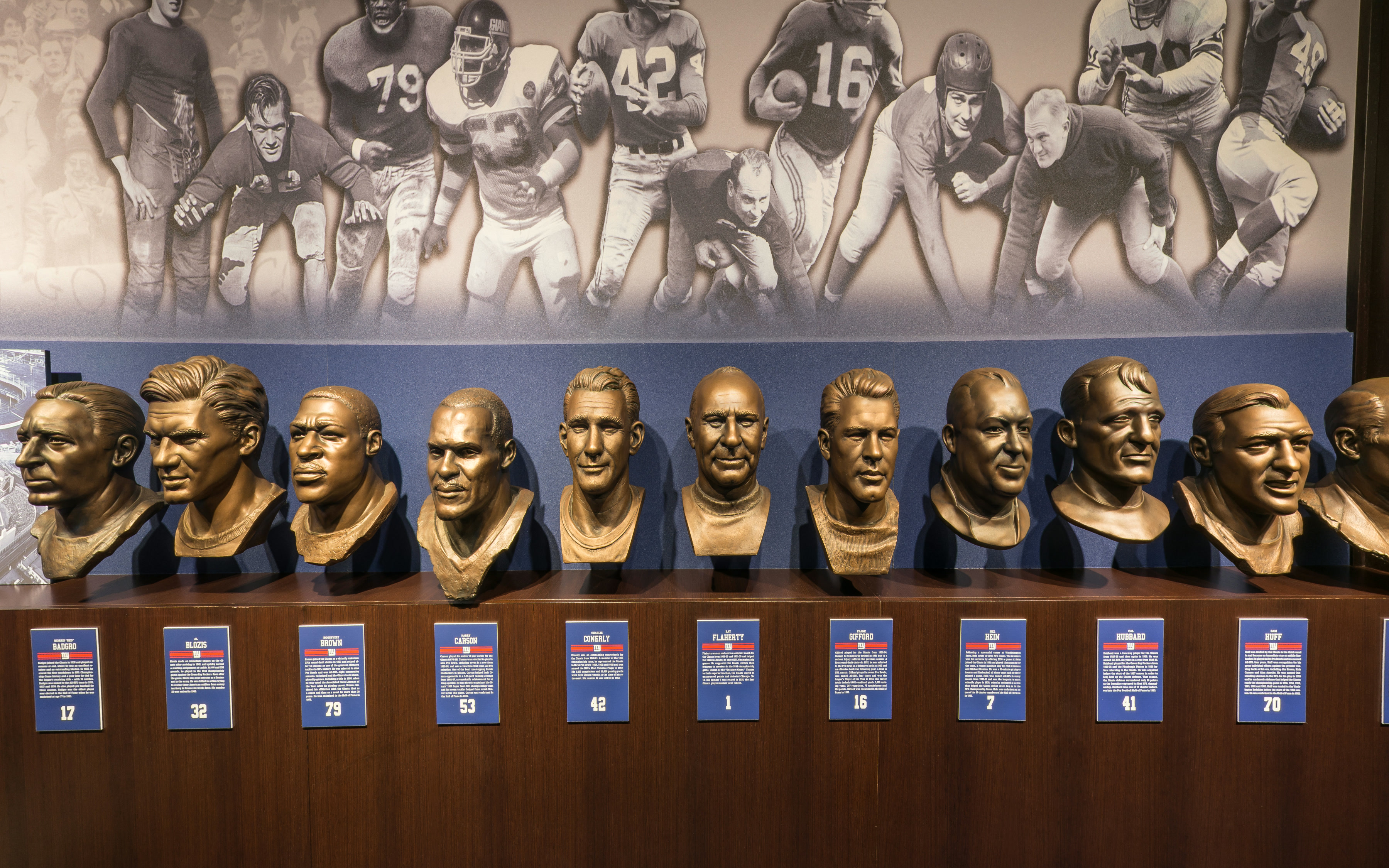 Bronze player busts and historic football imagery displayed in the Giants Legacy Club